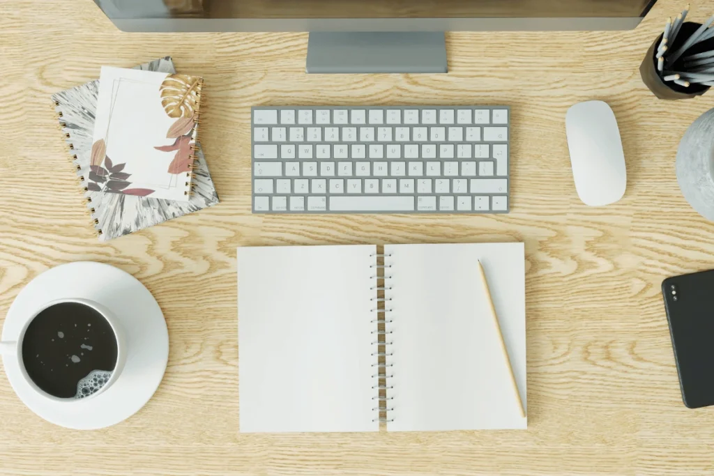A tidy desk with a computer monitor, keyboard, mouse, journal, and cup of coffee awaits an entrepreneur who is ready to refresh their website for the year